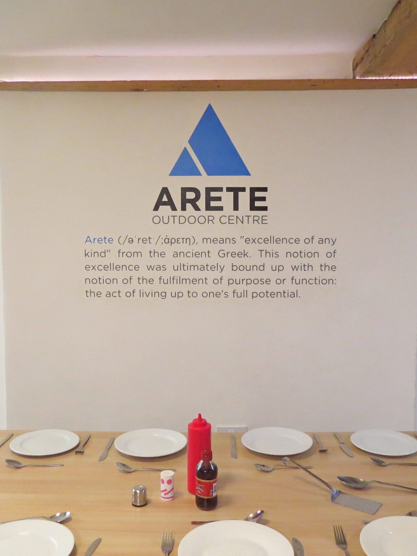 Table layed up for dinner underneath the Arete Outdoor Centre logo