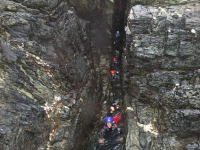 Coasteering through a narrow zawn on the sea cliffs of Anglesey, North Wales.